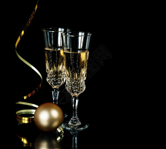 两杯香槟晶圣诞舞会和在黑色背景上隔离的金蛇纹有文字空间图片
