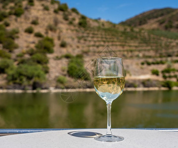 一杯白葡萄酒在葡萄牙杜罗河谷的游船甲板上品尝葡萄牙杜罗河游船上的一杯白葡萄酒图片