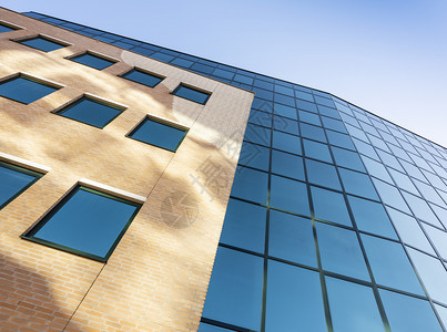 现代办公大楼的抽象部分以玻璃和钢铁表面有蓝色天空的反射图片