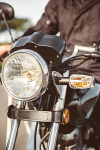 摩托车头灯特写与高级男子转向高级驾驶摩托车头灯图片