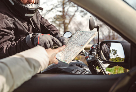 摩托车手询问驾驶员路线图的方向图片