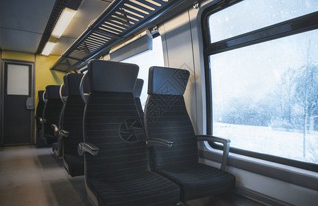 冬季旅行概念是德意志列车内部有黑色座位一排窗外有雪地自然景观暴风雪图片