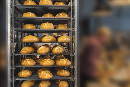 在金属架式车上新鲜烘烤的面包刚从满面的烤箱中取出并配有白面包图片