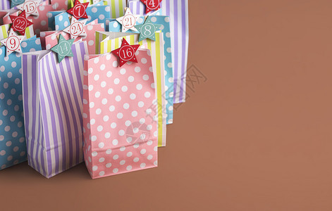 带有星形数字的彩色纸袋用于冒险日历概念在棕色背景上圣诞传统冒险日历有24种礼物图片