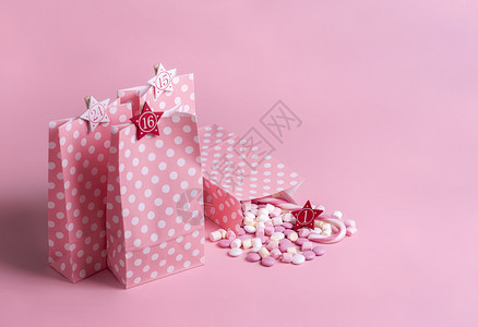 圣诞节进餐日历概念礼物袋装在粉红和白点上面有数字棉花糖果甘蔗圣诞传统框架图片