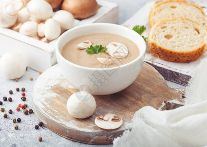 白碗盘奶油栗椰子香菇汤浅厨房背景和一盒生蘑菇新鲜面包图片