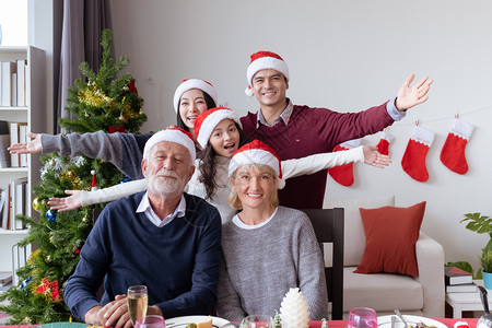 快乐的大家庭聚会和庆祝在圣诞节晚上餐厅与圣诞树一起装饰圣诞节日快乐的家庭节日概念图片