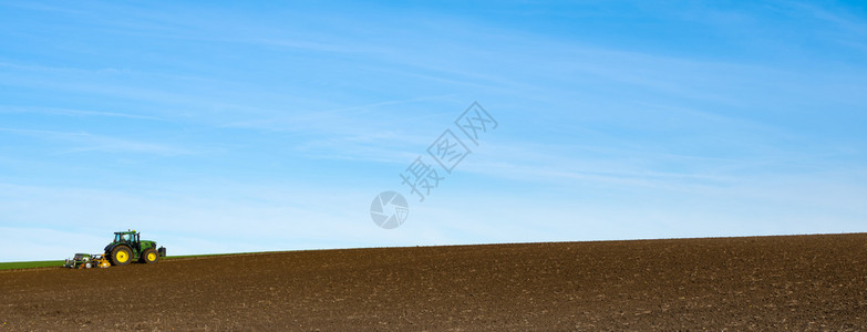在山上大片犁田的拖拉机在山丘上工作蓝天下地南林堡的杜特奇省工作用箭头耕种背景图片