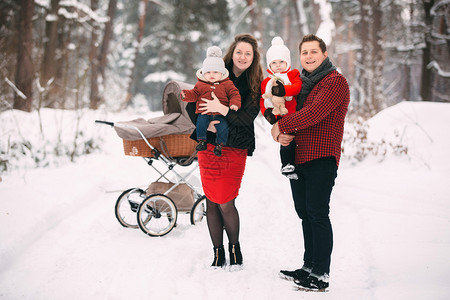 一对夫妇怀抱孩子在雪地与婴儿车留影图片