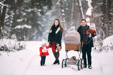 一对夫妇怀抱孩子在雪地与婴儿车留影背景图片