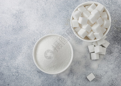白碗盘天然糖块和浅底色精制糖顶部视图图片