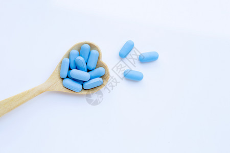 具有心脏形状的蓝医用药丸白色背景的木勺复制空间图片