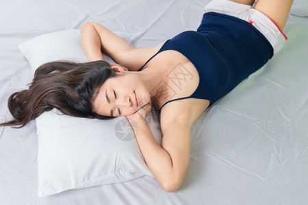 一位年轻迷人的亚洲女早上躺在床时伸出双手图片