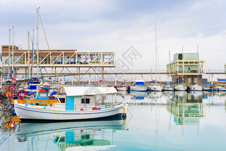 里马索市港景停泊的渔船在重天空下码头的餐馆和雨云辛普勒图片