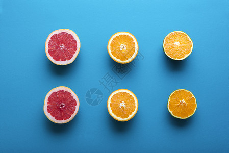 新鲜柑橘水果在蓝色背景下被一半切成两在橙子巧克力和葡萄汁一半的视野之上热带水果健康点心图片