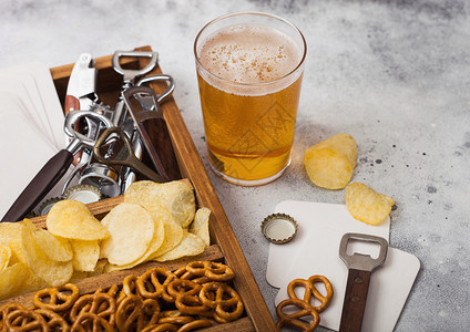 玻璃杯啤酒和开瓶器在轻厨房餐桌背景上放一盒零食图片