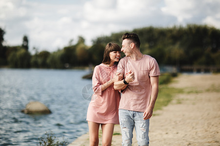 年轻情侣在湖边挽手散步图片
