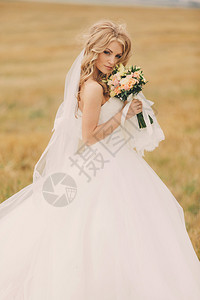 穿着豪华白色婚纱和玫瑰花束的美丽年轻新娘穿着豪华的白色婚纱和玫瑰花束的美丽年轻新娘穿着夏日盛装的可爱新娘肖像快乐结婚日带着化妆品图片