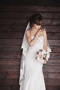 身着豪华白色礼服手拿着花束的美丽年轻新娘身着豪华白色礼服手拿着花束的年轻新娘图片