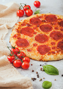 新鲜圆烤意大利面披萨西红柿在轻厨房餐桌背景上加巴西尔图片