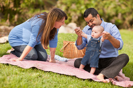 快乐的混合种族家庭在公园野餐图片