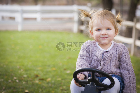 女孩开心的坐在玩具拖拉机上图片