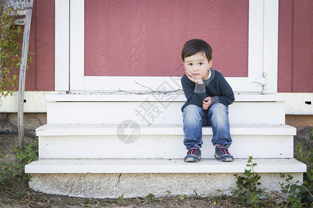 坐在谷仓的台阶上坐着放松的可爱混血男孩图片