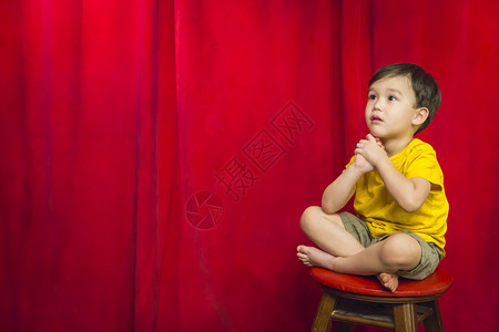 英俊的混血男孩坐在凳子上站红幕前图片