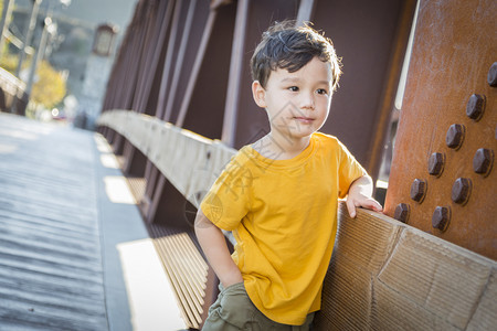 英俊的混种男孩仰赖在桥的户外图片