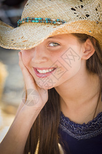 穿着牛仔帽的年轻前女孩肖像穿着牛仔帽在生锈的布景图片