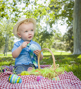 小男孩在公园野餐的毯子上玩彩色蛋壳背景图片