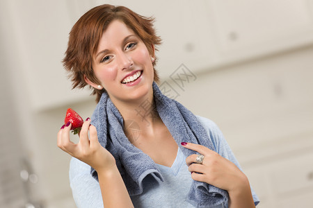 漂亮的红发女人毛巾在厨房里拿着草莓图片