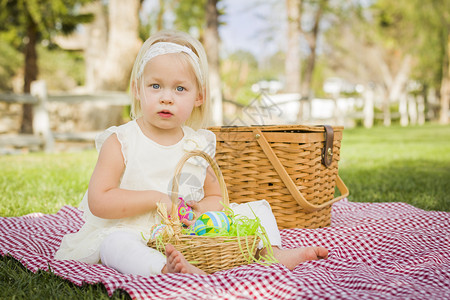 小女孩在公园野餐的毯子上玩彩色蛋壳背景图片