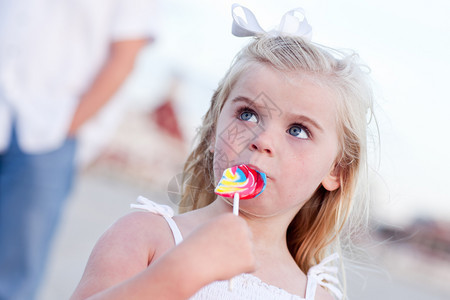 可爱的小女孩享受她的棒糖在海滩外面图片