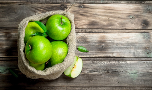 绿色苹果和切片在一个旧袋子里灰木底的色本绿苹果和切片在一个旧袋子里图片