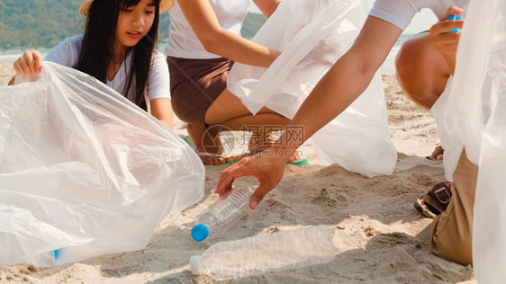 在海滩上收集塑料垃圾的年轻快乐家庭活动asi志愿者帮助保持自然清洁图片