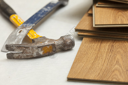磨损的锤子和玻璃棒与压层地板抽象图片