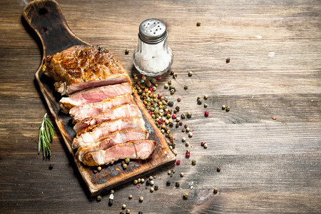 烤牛肉和香料在木制桌上图片