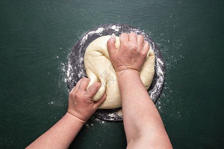 女人在面粉上绿色背景亲手打折准备比萨饼做披面团图片