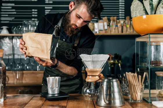 在咖啡店里用数字衡量咖啡身穿黑制服的纹手臂咖啡师图片