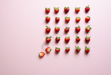 粉色背景的草莓对齐新鲜有机草莓绿色叶子图片