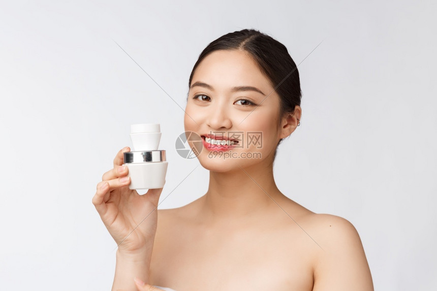 白孤立背景的美丽年轻女拿着化妆品面霜亚斯人白孤立背景的年轻美女
