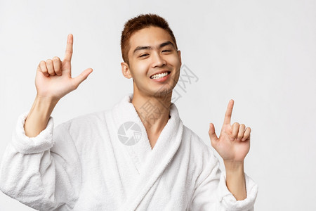 美丽的温泉和休闲概念喜悦英俊充满热情穿着浴袍亚洲男子肖像举起手指展示方式和跳舞欢乐的快白色背景美丽浴袍中的亚洲男子肖像展示方式和图片
