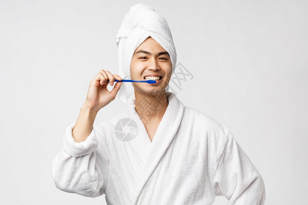 美丽spa和休闲概念穿着浴袍和巾的快乐亚洲人用牙刷和微笑照顾个人卫生白色背景穿浴袍和巾的快乐亚洲人图片