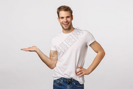 笑着快乐的金发年轻大胡子男在白色t恤介绍品中持有空白的复制间介绍图表或概念笑着白背景图片