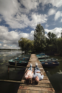 年轻夫妇躺在湖边的木桥上图片