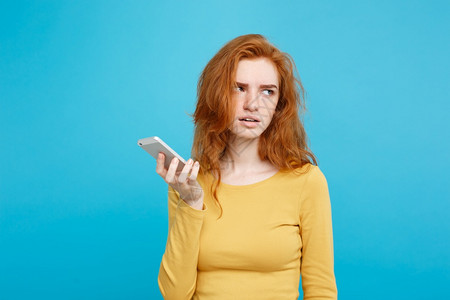 生活习惯与科技概念一个令人惊讶的穿着黄色礼服女孩在手机上交谈的肖像孤立在蓝色的糊面背景上复制空间生活方式与技术概念快乐的姜红头发图片