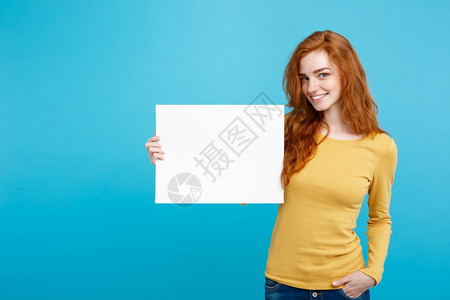 年轻漂亮的迷人姜红头发女孩微笑着空白的牌子蓝色面纸背景复制空间图片