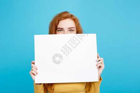 年轻美丽的红头发女孩微笑着空白的牌子蓝色面纸背景复制空间背景图片