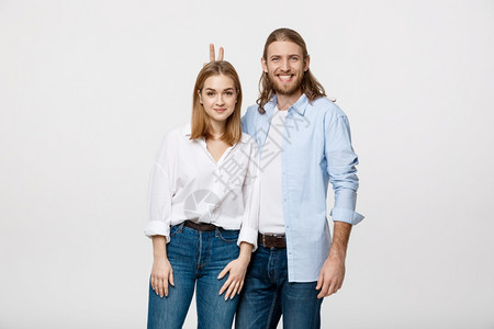 白色工作室背景中展示和平或胜利标志的可爱年轻夫妇肖像图片